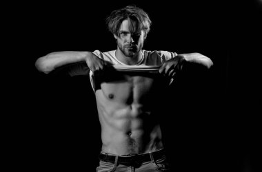 Beyaz tişörtlü yakışıklı adam seksi, kaslı gövdesini gösteriyor.