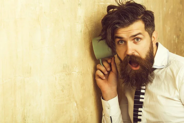 Uomo con la barba ascolta pettegolezzi con coppa . — Foto Stock