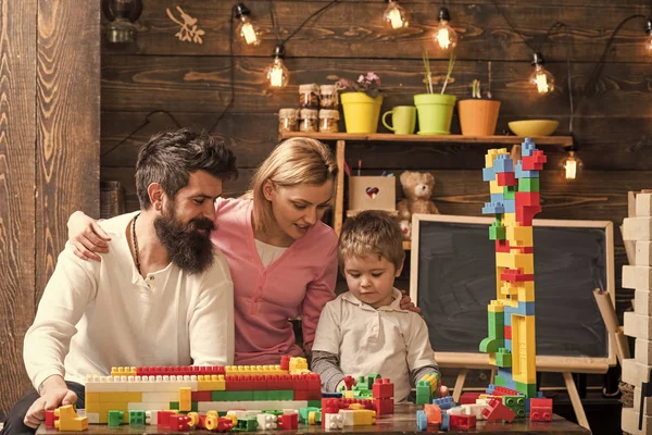父母拥抱, 看儿子玩耍, 享受亲子。家庭休闲概念。孩子与父母玩塑料积木, 建造建筑。父亲, 母亲和可爱的儿子玩构造砖 — 图库照片