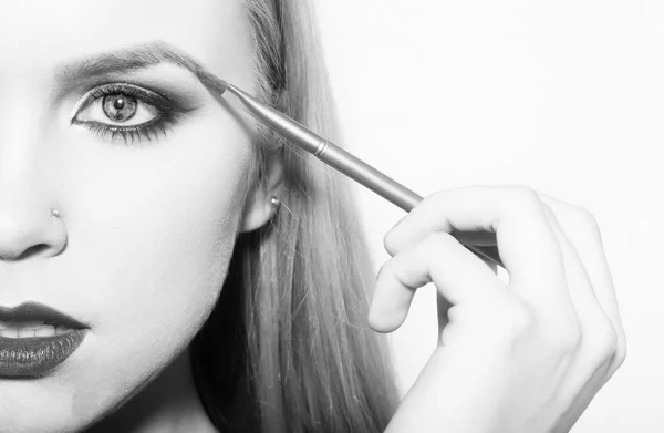 Girl half face drawing eyebrow with makeup brush