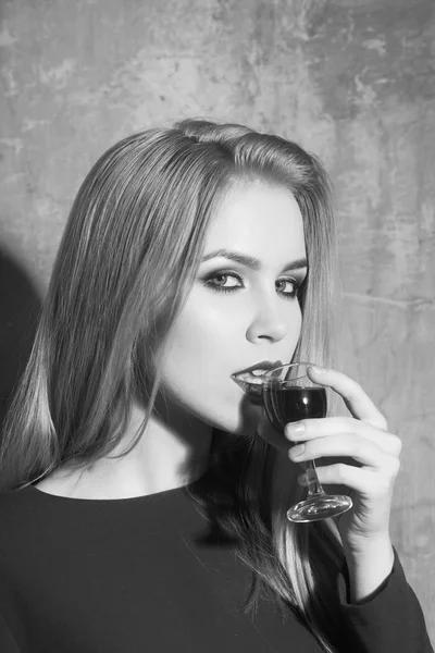 Woman drinking glass of red liqueur