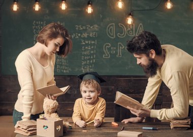 Baba ve oğulları, arka plan kara tahta öğretim kitap, okuma anne. Aile eğitimi oğulları hakkında umurunda değil. Lisansüstü şapkalı çocuk çocuk dinleme öyküleri seviyor. Evde eğitim kavramı.
