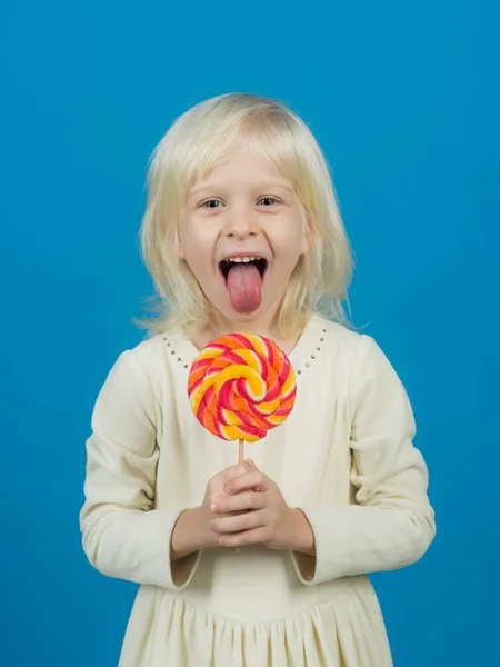 Get lost in the hypnotic swirl. Happy candy girl. Little girl hold lollipop on stick. Little child with sweet lollipop. Happy childhood food