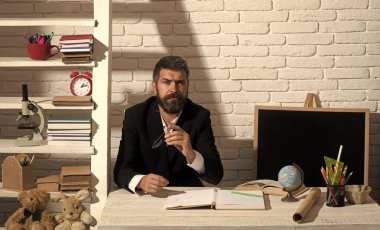 Profesör düşünceli yüz ifadesi ile masa başında oturur