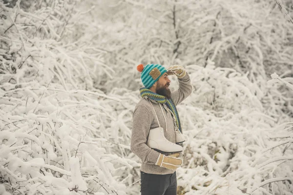 ひげを生やした幸せな男は、雪に覆われた冬の森、クリスマスでスケートを保持します。 — ストック写真