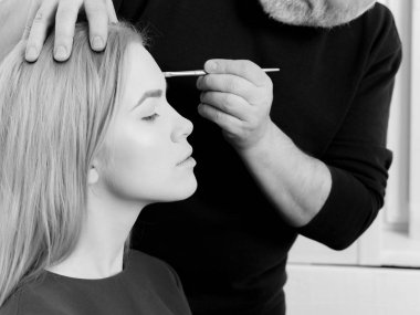 Kadın erkek elinde fırça ile yüz makyaj elde