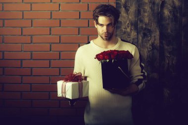 sakallı adam tutar kırmızı gül çiçek ve hediye kutusu