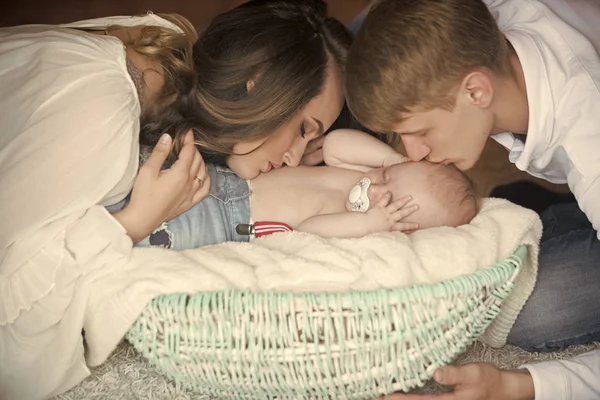 Woman, man kiss newborn child sleep in crib on floor