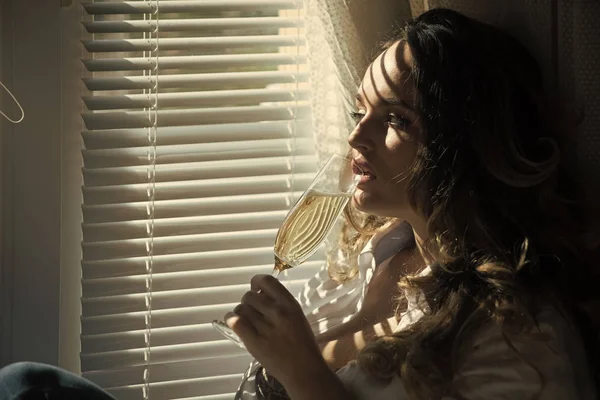Chica con pelo largo rizado beber champán en la ventana — Foto de Stock