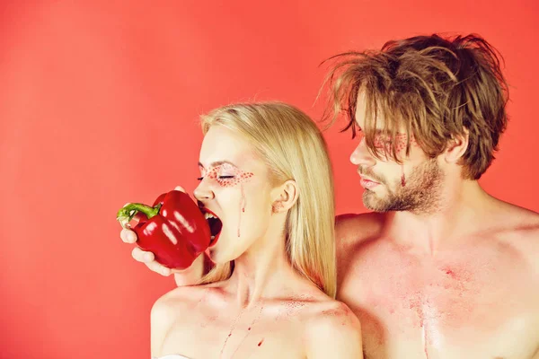 Чоловік і жінка з гримом кусають солодкий перець — стокове фото