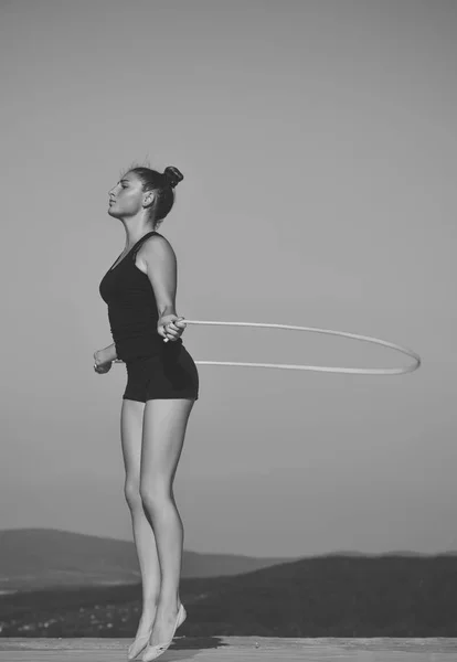 Woman gymnast in black sportswear with green jump rope