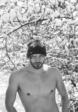 ciddi sakallı yakışıklı genç veya çıplak gövde ve göğüs üzerinde seksi kaslı adam uygun vücut kış şapka güneşli ağaçlar karla doğal zemin üzerine açık.