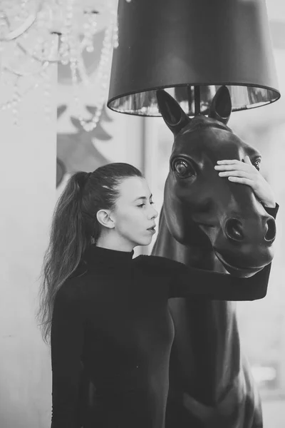 Frau im ganz schwarzen Outfit hält Skulptur von Pferdekopf. — Stockfoto