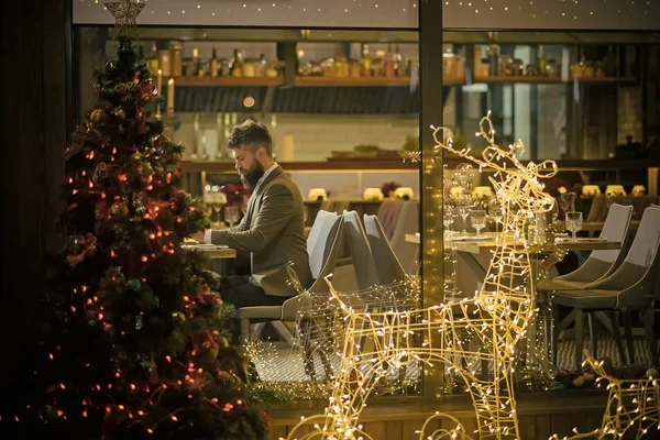 Man hipster sit at Christmas tree in restaurant