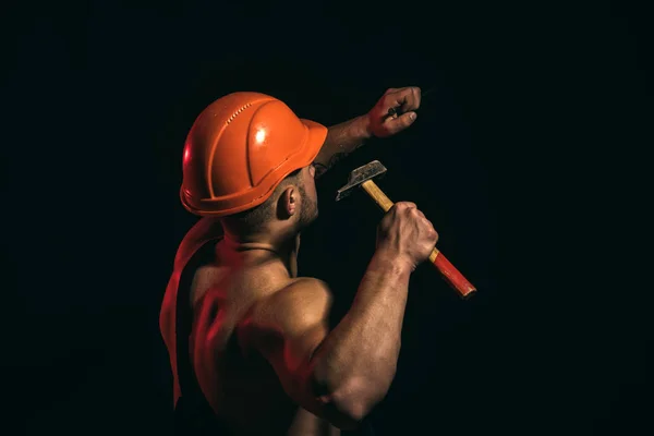 Still under construction. Hard worker use muscular strength. Man work with hammer. Construction worker hammer a nail. Muscular man builder at work under construction