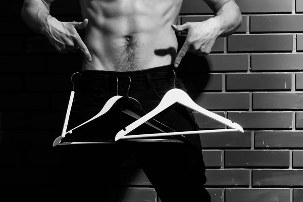 Muscular macho man with sexy six packs holds hangers — Stock Photo, Image