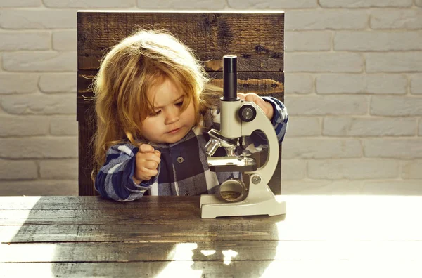 Студентський хлопчик з мікроскопом навчання на освітньому робочому місці — стокове фото