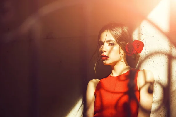 빨간 드레스와 베이지색 벽에 서 있는 머리에 장미 소녀 — 스톡 사진