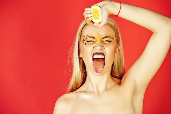Mooie blonde vrouw met creatieve modieuze make-up drank citroen, vitamine — Stockfoto