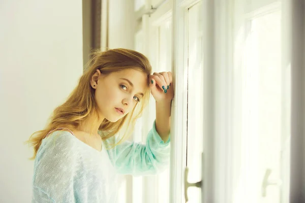 Chica bonita con ojos azules de pie en la ventana — Foto de Stock