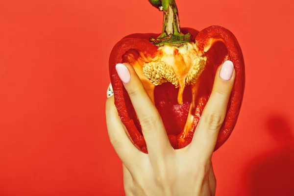 Paprika in hand van meisje op rode achtergrond — Stockfoto