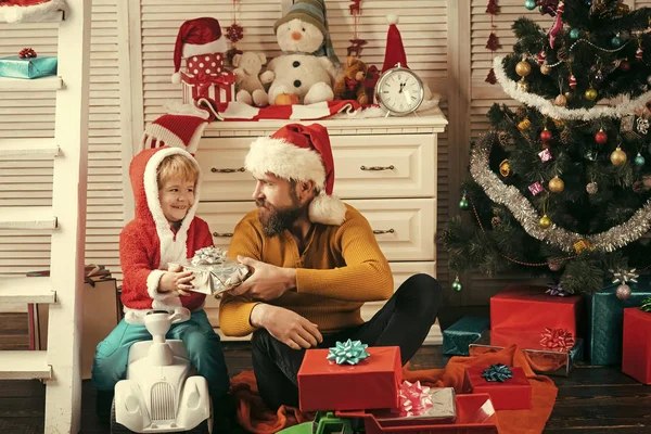 Santa claus kid en bebaarde man bij kerstboom. — Stockfoto