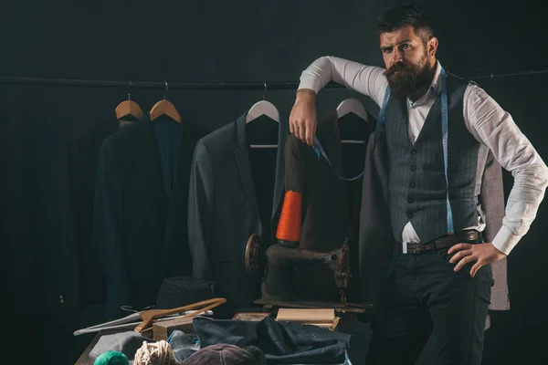 Considering the next step. business dress code. Handmade. sewing mechanization. retro and modern tailoring workshop. Bearded man tailor sewing jacket. suit store and fashion showroom. Tailor sewing