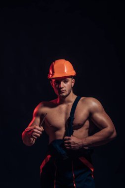 Güvenli tutmak. Çivi kaslı adam. İnşaat işçisi veya Oluşturucu pazı triceps ile. Kaslı kolları olan güçlü adam. İşçi veya işçi kask içinde. Çalışkan