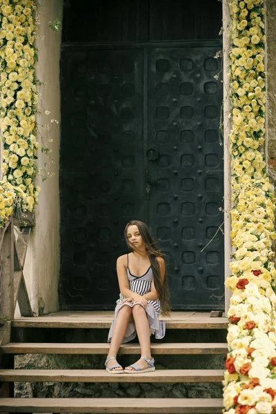Adorable niña sentada en las escaleras con flores —  Fotos de Stock