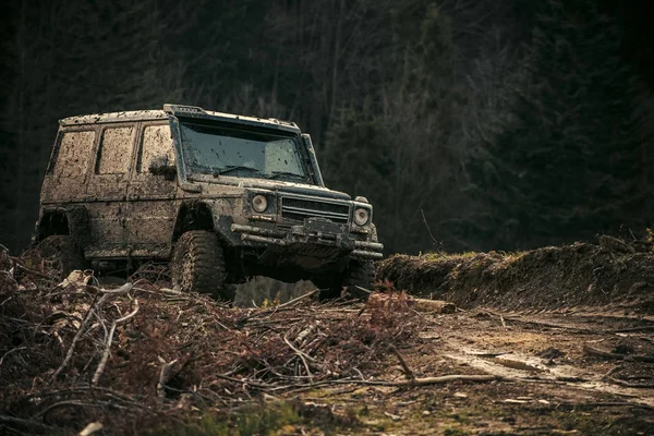Verschmutzter Geländewagen mit dunklem Wald im Hintergrund, defokussiert. — Stockfoto