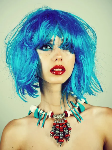 Fashion model with naked body and red lips. Girl with bright artificial hair in ethnic jewelry. Beauty and fashion. Woman in blue wig with fashionable makeup. Hairdresser salon and barbershop.