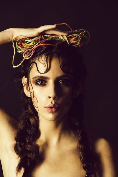 girl with braids holding colorful threads on head