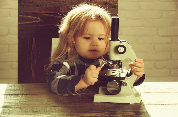 Мальчик студент учится на рабочем месте с микроскопом — стоковое фото