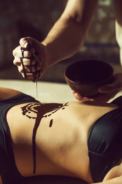 Kvinnliga sexiga mage och manliga händer på chokladmassage — Stockfoto