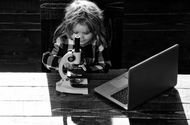 Eğitim kavramı, çocuk öğrenci işyerinde mikroskopla, dizüstü bilgisayar