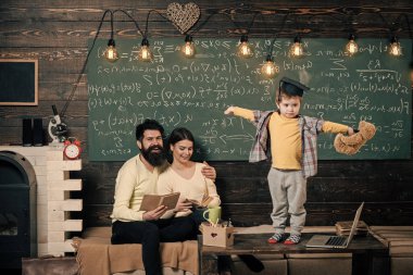 Destek kavramı. Çocuk oyuncak ayı ve gerçekleştirme tutar. Çocuk Anne ve baba için onun bilgi sunma. Oğulları, kara tahta arka plan dinleme anne. Lisansüstü şapkalı akıllı çocuk gibi gerçekleştirmek için.