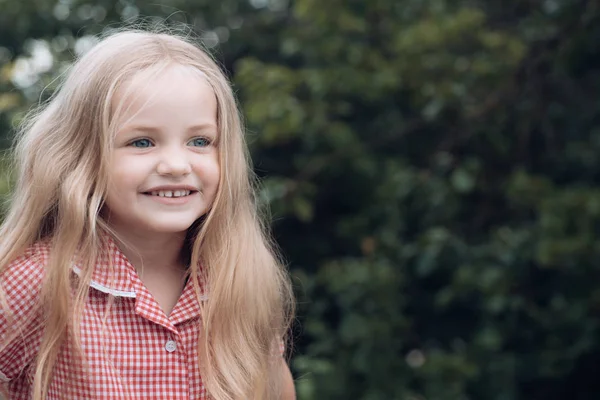 Sono troppo felice di essere me stesso. Bambino piccolo felice sorridente. Ragazzina con i capelli biondi. La ragazzina indossa i capelli lunghi. Bambino felice con un sorriso adorabile. Vento gioca nei miei capelli — Foto Stock