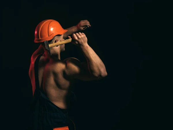 Le projet est actuellement en construction. L'homme travaille avec le marteau. Travailleur de la construction marteau un clou. Homme musclé constructeur au travail en cours de construction. Travailleur dur utiliser la force musculaire, l'espace de copie — Photo