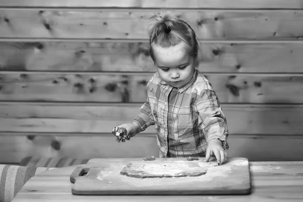 Carino bambino cucina con pasta e farina, tiene stampo metallico — Foto Stock