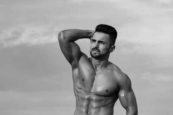 Modelo hombre con cuerpo muscular en el cielo azul —  Fotos de Stock