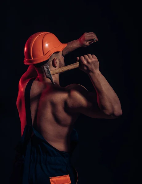 Het is in aanbouw. Harde werker gebruik spierkracht. Bouwvakker hammer een spijker. Gespierde man bouwer op het werk in aanbouw. Werk van de man met de hamer — Stockfoto