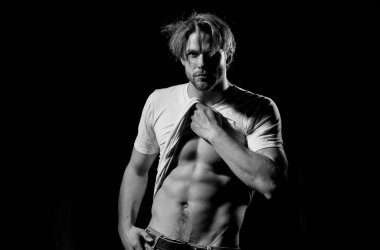 Beyaz tişörtlü yakışıklı adam seksi, kaslı gövdesini gösteriyor.