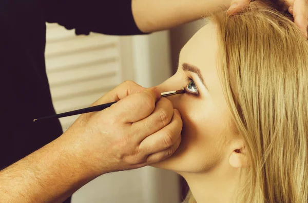 Maquillaje artista aplicando sombras en los ojos de mujer — Foto de Stock