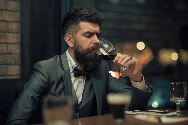 bar customer sit in cafe drinking alcohol. Bearded man rest in restaurant with wine glass. Perfect wine. Date meeting of hipster awaiting in pub. Businessman with long beard drink in cigar club.