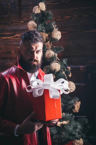 Weihnachtsmann in moderner roter Jacke. Weihnachtsbaum auf hölzernem Hintergrund. Weihnachtsmann mit Geschenk. Weihnachtswünsche werden wahr, wenn Sie glauben. — Stockfoto