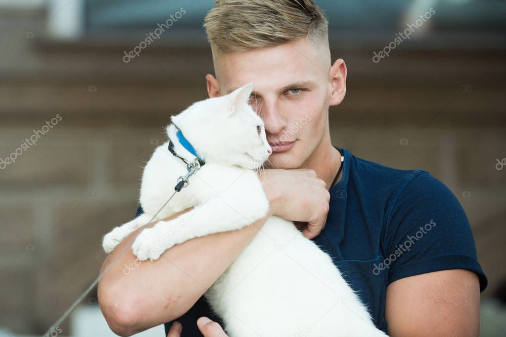 He is more than just a pet. Happy cat owner with muscular look. Cat relaxes in arms of his owner. Happy man on walk with cat pet. Muscular man hold cute pedigree cat