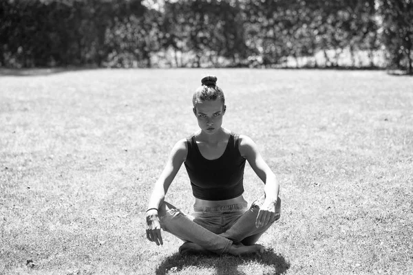 Pretty girl sits in yoga position on grass — Stock Photo, Image