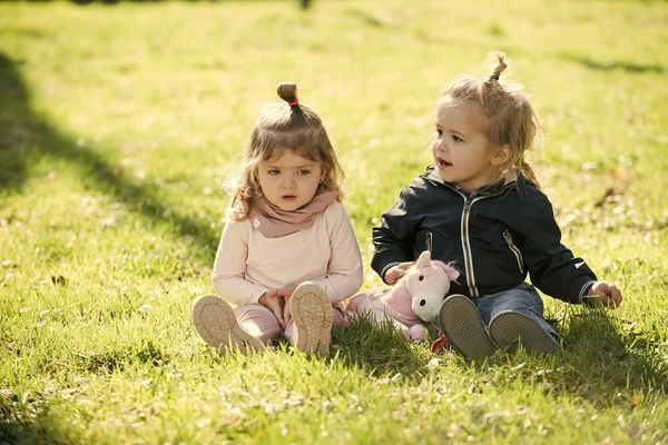 Meisje en jongen zitten op groen gras — Stockfoto