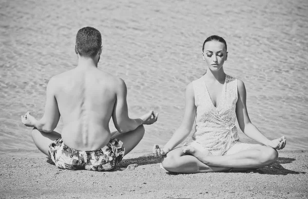 yoga couple relaxing doing meditation on beach