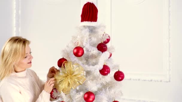 La mujer decora el árbol de Navidad. Los regalos de Año Nuevo y el regalo de preparación. Feliz Navidad y Feliz Año Nuevo . — Vídeos de Stock